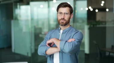 Mutlu, arkadaş canlısı, sakallı, modern cam ofis işyerine bakan iş adamı portresi. Başarılı, çekici, güler yüzlü, serbest girişimci.