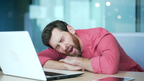 仕事の時間に職場で寝そべっているフリーランスの熟練したビジネスマン疲れた過労者の肖像コンピュータの横に座って机の上に眠っている起業家 — ストック動画