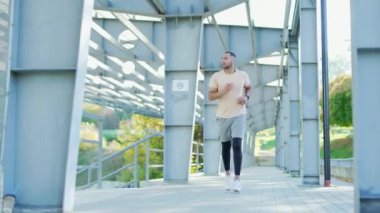 Şehrin sokaklarında koşan yetişkin bir koşucu. Eşofmanlı yakışıklı bir adam günlük koşusunu şehir stadyumunda yapıyor. Spor ve sağlıklı yaşam tarzı kavramı