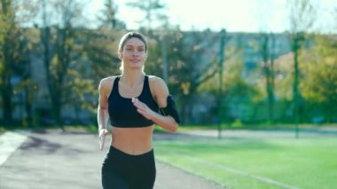 Yetişkin atletik kadın bir şehir stadyumunda koşuyor. Eşofmanlı güzel ve fit bir kadın günlük koşusunu sokakta yapıyor. Sağlıklı genç bir sporcu kadın antrenmanla meşgul. Spor konsepti