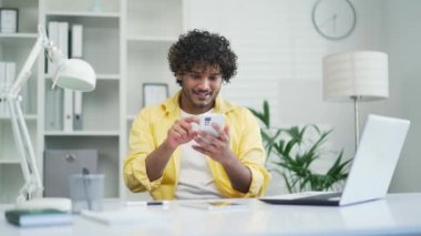 Neşeli serbest girişimci, online zaferi kutluyor. Ofiste oturuyor, cep telefonu kontrol ediyor. E-posta uygulaması. Heyecanlı görün.