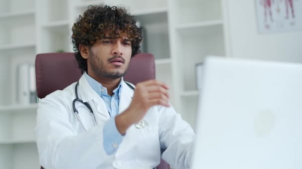 Przemyślany Młody Człowiek Lekarz Pracuje Laptopie Biurze Nowoczesnej Kliniki Lub — Wideo stockowe