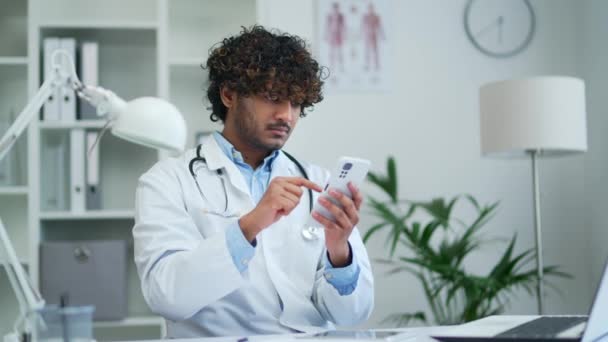 Läkare Använder Telefonen Arbetar Medan Sitter Ett Modernt Kontor Klinik — Stockvideo