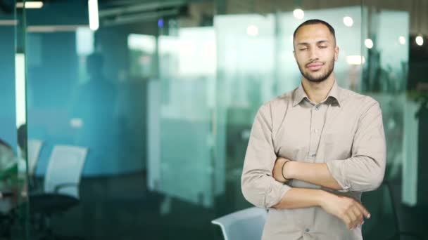 シャツの若い男は 現代のオフィスに立っている間 テキストをコピーするための空のスペースに指を示しています カメラを見てハンサムな混合レースビジネスマン笑顔 広告用テンプレート — ストック動画