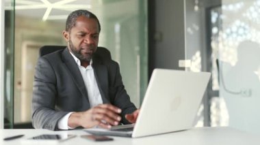 Modern ofiste otururken bilgisayar programının kötü performansından şikayet eden sinirli bir adam. Öfkeli işadamı bir bilgisayarın, internetin veya servisin çalışmalarından memnun değil