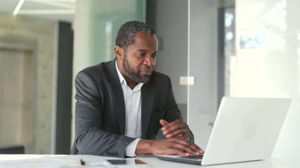 一位成熟的非洲裔美国人 坐在现代化办公室的办公桌前 一边在笔记本电脑上工作 一边感到恶心 中年男子中毒 肚子痛 — 图库视频影像