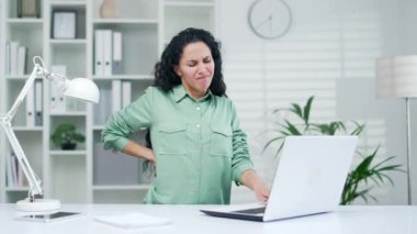 Modern işyeri girişimcisi ofis çalışanlarının bilgisayarlarında çok çalıştıktan sonra sırtı ağrıyan çok çalışan bir iş kadını, iç mekanlarında gerilimden muzdarip.