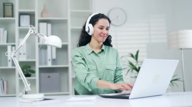 Kıvırcık esmer, laptopta çalışan, müzik dinleyen ve modern ofiste kulaklıkla radyo dinleyen genç bir bayan işçi. Kapalı alanda çalışmaktan hoşlanan hoş bir kız öğrenci.