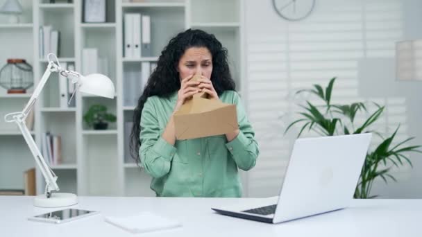 職場のオフィスで働く若い女性がパニック発作を起こし おびえた女性が紙袋に息を吹き込む — ストック動画