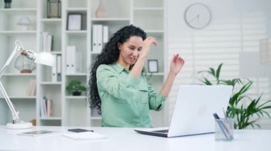Neşeli, genç İspanyol kadın ofis çalışanı iş yerinde dans projesini tamamladı. Kadın iş kadını, ajan, çalışan ya da serbest çalışan ev bilgisayarında yapılan çalışmalardan memnun.