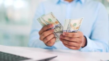 Erkek eli kapalı, 100 dolarlık banknotları sayıyor. Gömlekli bir iş adamı, modern bir ofisteki bir çalışma masasında banknotları sayar. Bir adamın elinde nakit para vardır. Mali başarı kavramı