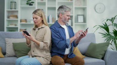 Karı koca, birbirlerine kırgınlar, akıllı telefonlarına bakarlar evdeki kanepede yan yana otururken. Evli bir çiftin anlaşmazlığı. Aile ilişkilerinde sorun ve kriz