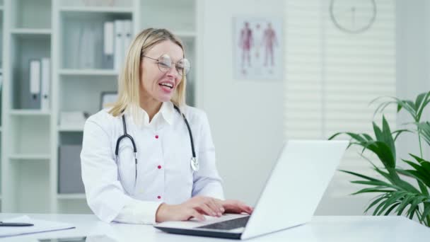 Dojrzała Lekarka Białym Płaszczu Rozmawia Przez Telefon Laptopem Klinice Szpitalnej — Wideo stockowe