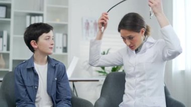 Kadın çocuk doktoru, modern bir klinik ya da hastanenin muayenehanesinde ciğerlerine steteskop dayamış küçük bir hastanın kalp atışlarını dinliyor. Kadın terapist doktor bir çocuğun sağlığını kontrol ediyor.