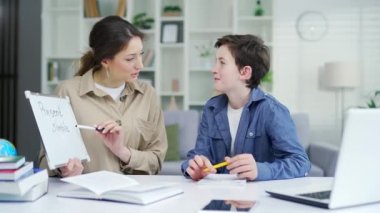 Özel öğretmen çocuğa ödevini yapmasını öğretiyor liseli çocuğa dil konusunda yardım ediyor. Anne oğluna yardım ediyor çocuk okul çocuğu ev dersi eğitimine hazırlanıyor.