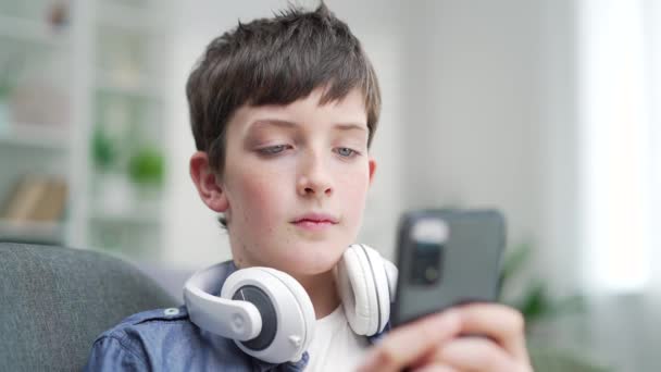 Schuljunge Benutzt Smartphone Während Hause Auf Der Couch Sitzt Indoor — Stockvideo