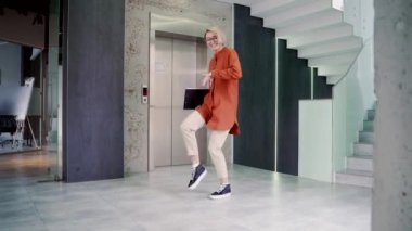 Koridorda ya da modern iş merkezinin salonunda zafer dansı yapan neşeli, genç ve çekici bir kadın. Kadın ofis çalışanı başarısını neşeyle kutluyor. Komik bir çalışanın zafer dansı