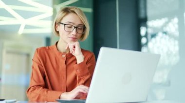 Modern ofiste çalışırken dizüstü bilgisayarla çalışan düşünceli genç bayan çalışanlar. Ciddi kadın yönetici sorunu çözmeyi düşünür, internetteki bilgileri analiz eder.