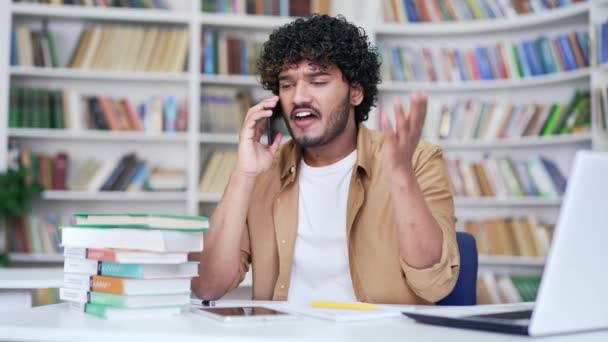 Dühös Egyetemi Hallgató Aki Okostelefonon Vitatkozik Miközben Egyetemi Könyvtárban Ideges — Stock videók