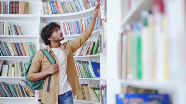 Студент Выбирает Книгу Библиотеке Кампуса Красивый Мужчина Учится Экзамене Университете — стоковое видео