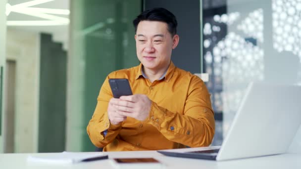 Sorrindo Asiático Homem Negócios Camisa Usando Smartphone Enquanto Sentado Mesa — Vídeo de Stock