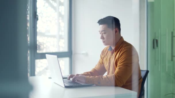 Widok Boku Przemyślany Azjatycki Biznesmen Pracujący Laptopie Siedząc Przy Biurku — Wideo stockowe
