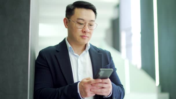 Sorrindo Asiático Empresário Terno Formal Óculos Está Usando Smartphone Enquanto — Vídeo de Stock