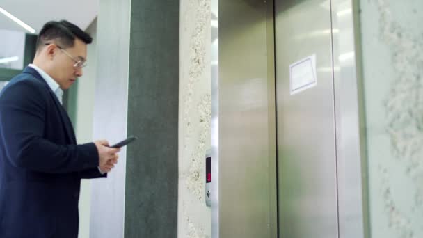 Азиатский Бизнесмен Вызывает Лифт Помощью Смартфона Время Просмотра Современном Офисном — стоковое видео