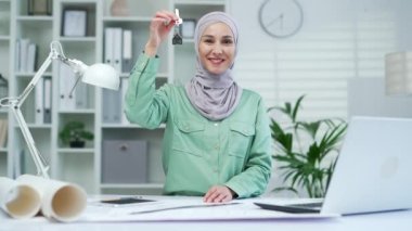 Müslüman kadın emlakçı elinde modern ofis binasının anahtarını tutuyor. Mali konut kredisi ya da ev satın almak için biriktirilen para, gayrimenkul ve sigorta tasarımcısı ya da mimar.