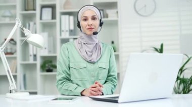 Portre şirketinin müşteri destek servisi yardım hattında gülümseyen kadın temsilci kablosuz kulaklıkla çağrı merkezi temsilcisi müşteriye ofisindeki kameraya bakarak şikâyetlerde yardımcı oluyor.