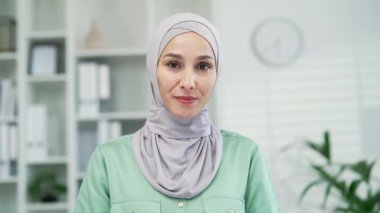 Webcam görüntüsü, gülümseyen genç çalışan işkadını kameraya bakıyor ve çevrimiçi kurs toplantısı konferansı dinliyor. Modern ofis işyerindeki kapalı mekan Webinar öğretmeni POV ekranında görüntülü konuşma yapıyor.