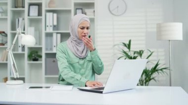 Mide bulantısı çeken Müslüman kadın, modern ofiste çalışırken dizüstü bilgisayarda kusmak istiyor. Hasta Arap tesettür çalışanı gıda zehirlenmesi ve kapalı alanda sindirim sorunu yaşıyor.