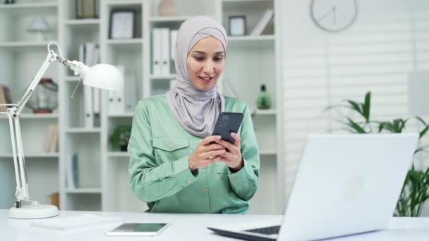 Радостная Молодая Мусульманская Предпринимательница Хиджабе Счастливо Прочитала Сообщение Смартфоне Рабочем — стоковое видео