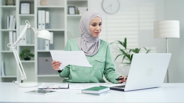 幸せなイスラム教徒のアラビア語の女性の金融会計士は良い財務結果でレポートと喜びを計算します満足した女性起業家や中小企業の所有者は ドキュメントPcで作業紙の仕事は喜びです — ストック動画