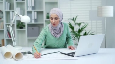 İslami kadın mimar, çizimlerle masa başında çalışan yaratıcı iç mimar. Ofisteki Arap kadın bir apartman veya ev inşaatı ve ev yenileme konsepti tasarlıyor