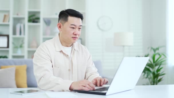 快乐的亚洲人在庆祝商业成功的同时 还坐在总部办公室的办公桌前 在笔记本电脑上阅读着好消息 兴奋的男人满足于一个愉快的通知 表现出一个肯定的信号 — 图库视频影像