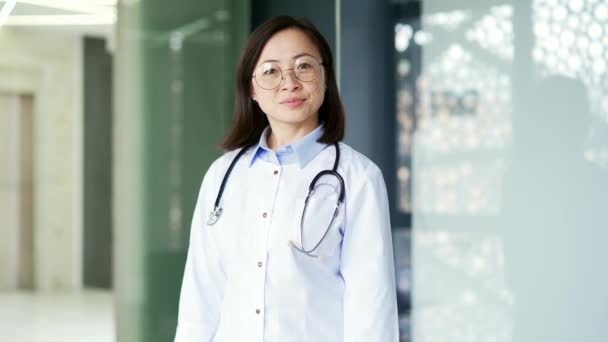 Портрет Серозной Азиатки Белом Халате Очках Смотрящей Камеру Современной Больничной — стоковое видео