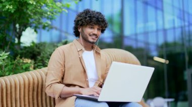 Kulaklıklı genç bir işadamı, bir ofis binasının yanındaki bankta otururken dizüstü bilgisayarla yazı yazıyor. Freelancer çevrimiçi sohbet ediyor, bir mesaj yazıyor, e- postaları kontrol ediyor, bir istemciyle uzaktan iletişim kuruyor