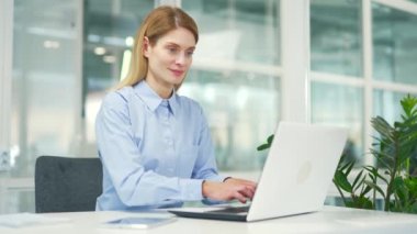 Olgun bir iş kadını, modern ofisteki çalışma masasında otururken dizüstü bilgisayarda daktilo kullanıyor. Bilgisayarda bir proje üzerinde çalışan gülümseyen kadın çalışanlar, bir müşteriye mesaj atmak, internette sohbet etmek.