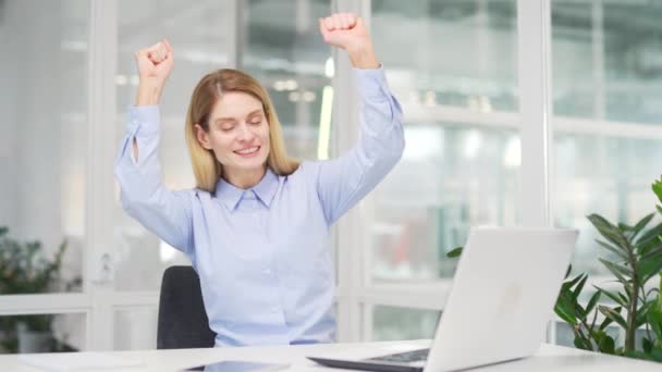 快乐的女商人坐在现代办公室的办公桌前 在笔记本电脑上完成了工作 微笑满足女性员工的喜悦 庆祝项目的完成 完成的工作 — 图库视频影像