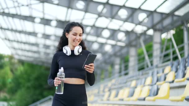 Joven Deportista Feliz Usando Teléfono Inteligente Mientras Camina Por Estadio — Vídeo de stock