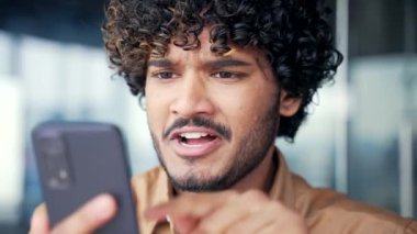 Kapatın. Kızgın, modern ofiste otururken akıllı telefondan kötü haberler okuyan stresli bir çalışan. Endişeli deli adam cep telefonundaki mesaja bakarken bağırıyor ve tartışıyor.