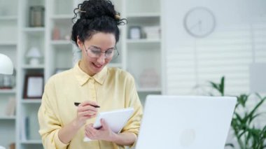 Bayan öğrenci online e-öğrenim dinliyor, evdeki masada oturan uzaktan kumandalı bir öğretmen. Uzaktan öğrenme seminerinde bir kadın dizüstü bilgisayarla özel öğretmenle iletişim kurar.