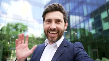 İş adamı, ofis binası dışında takım elbiseli bir iş adamı. Akıllı telefona bak. Gülümsüyor ve uzaktan sosyal medyada iş arkadaşlarıyla konuşuyor.