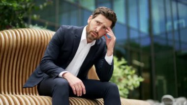 Ofis binasının yanındaki bankta oturan resmi takım elbiseli depresif iş adamı girişimci. Depresyonda olan üzgün erkek yatırımcı zihinsel sağlık sorunları yaşıyor