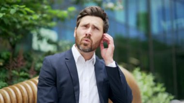 Kulak ağrısından muzdarip, sakallı, olgun bir ofis çalışanı, kulak iltihabı olan bir adam hassas kulaklara dokunur. Erkek bağırışları acıdan, iltihaptan kulak iltihabından, kulak iltihabından, Yaralı Alevler 'den