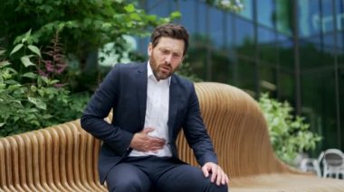 Mide bulantısı ya da zehirlenme geçiren bir iş adamı şehir dışındaki bir bankta oturuyor. Olgun çalışan yetişkin erkek ofis çalışanı hazımsızlık çeken karın ağrısı çekiyor.