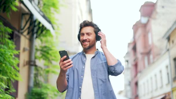 Mutlu Yetişkin Yakışıklı Sakallı Adam Şehir Caddesinde Yürüyor Kablosuz Kulaklıkla — Stok video