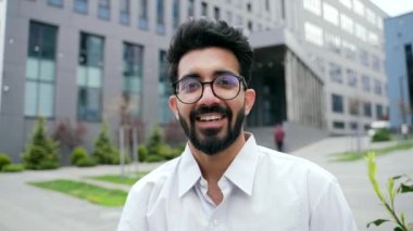 POV, bir ofis binasının yanında dikilirken akıllı telefon kullanan genç bir adamın video görüşmesini kapat. Beyaz tişörtlü mutlu sakallı erkek bir arkadaşıyla sohbet ediyor.