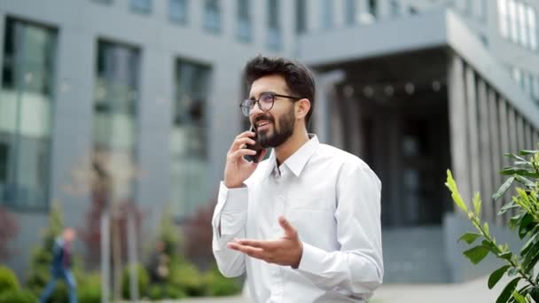 Joven Hombre Negocios Sonriente Hablando Teléfono Inteligente Mientras Está Parado — Vídeos de Stock